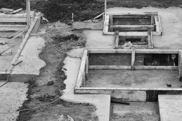 Casseforme di legno vuote montate su un getto di fondazione in cantiere, viste dall’alto, fotografia in bianco e nero