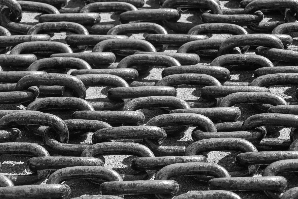 Black-and-white photograph of rows of metal chain links, each one hooked into the next