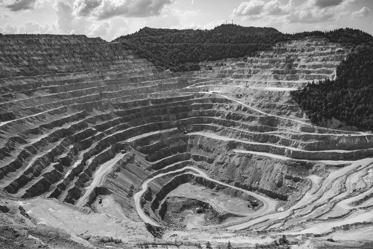 Vista aerea di una cava a cielo aperto con terrazzamenti a gradoni concentrici, fotografia in bianco e nero