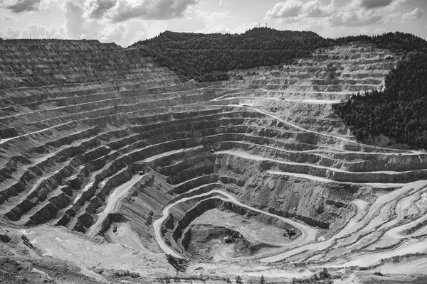 Vista aerea di una cava a cielo aperto con terrazzamenti a gradoni concentrici, fotografia in bianco e nero