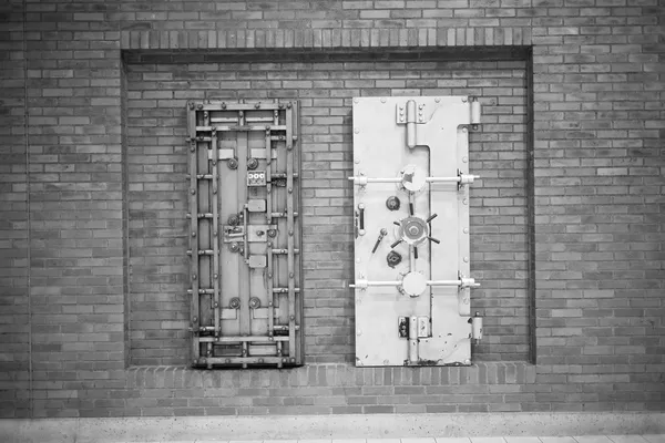 Two armoured vault doors set into a brick wall