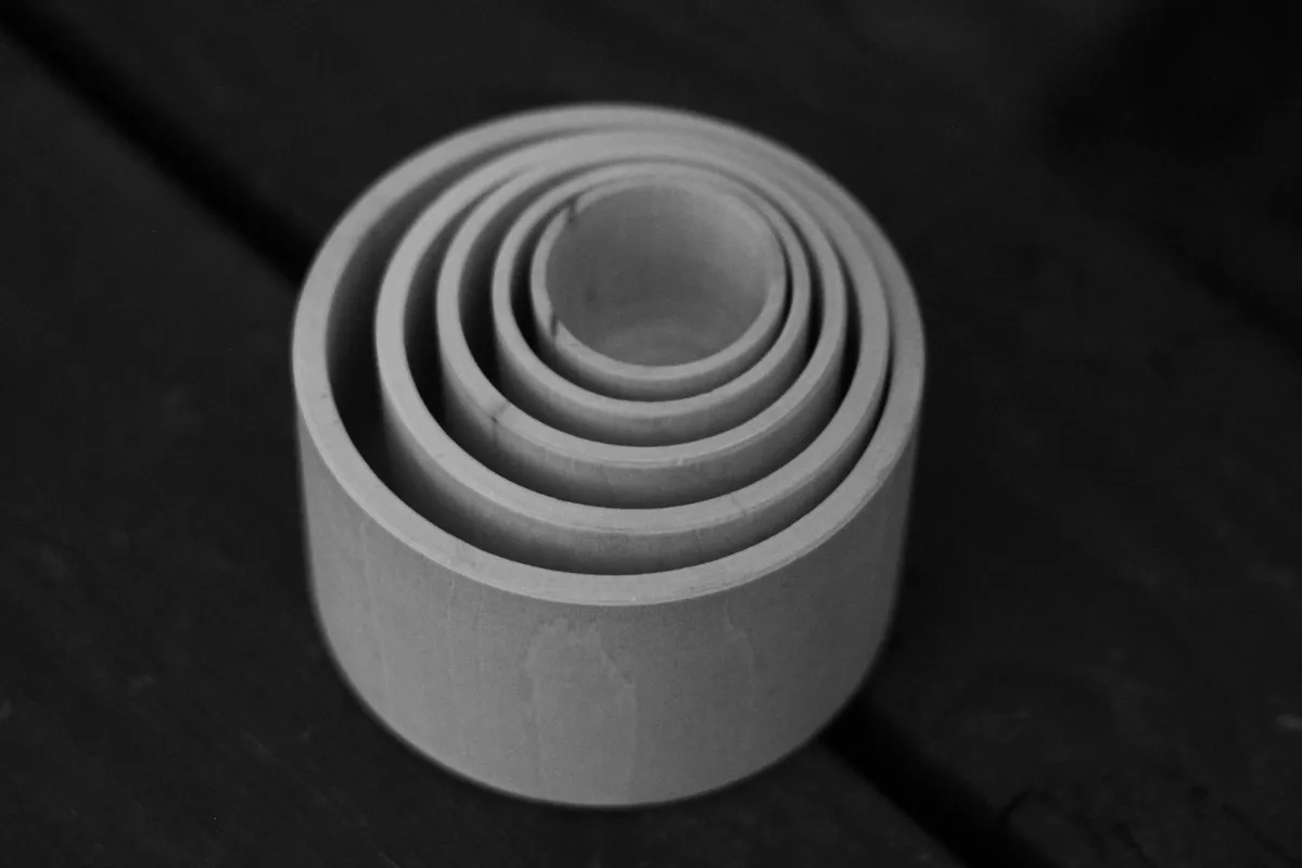 A series of pale wooden rings nested one inside the other, photographed from above, in black and white