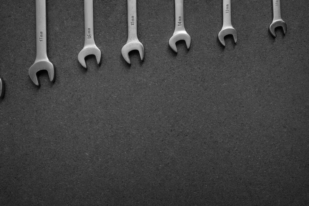 A row of open-end spanners in different sizes on a dark surface, in black and white