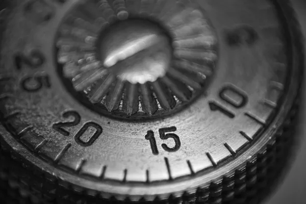 Black and white macro of a graduated metal dial, with the numbers 10, 15, 20 and 25 engraved around a central pin