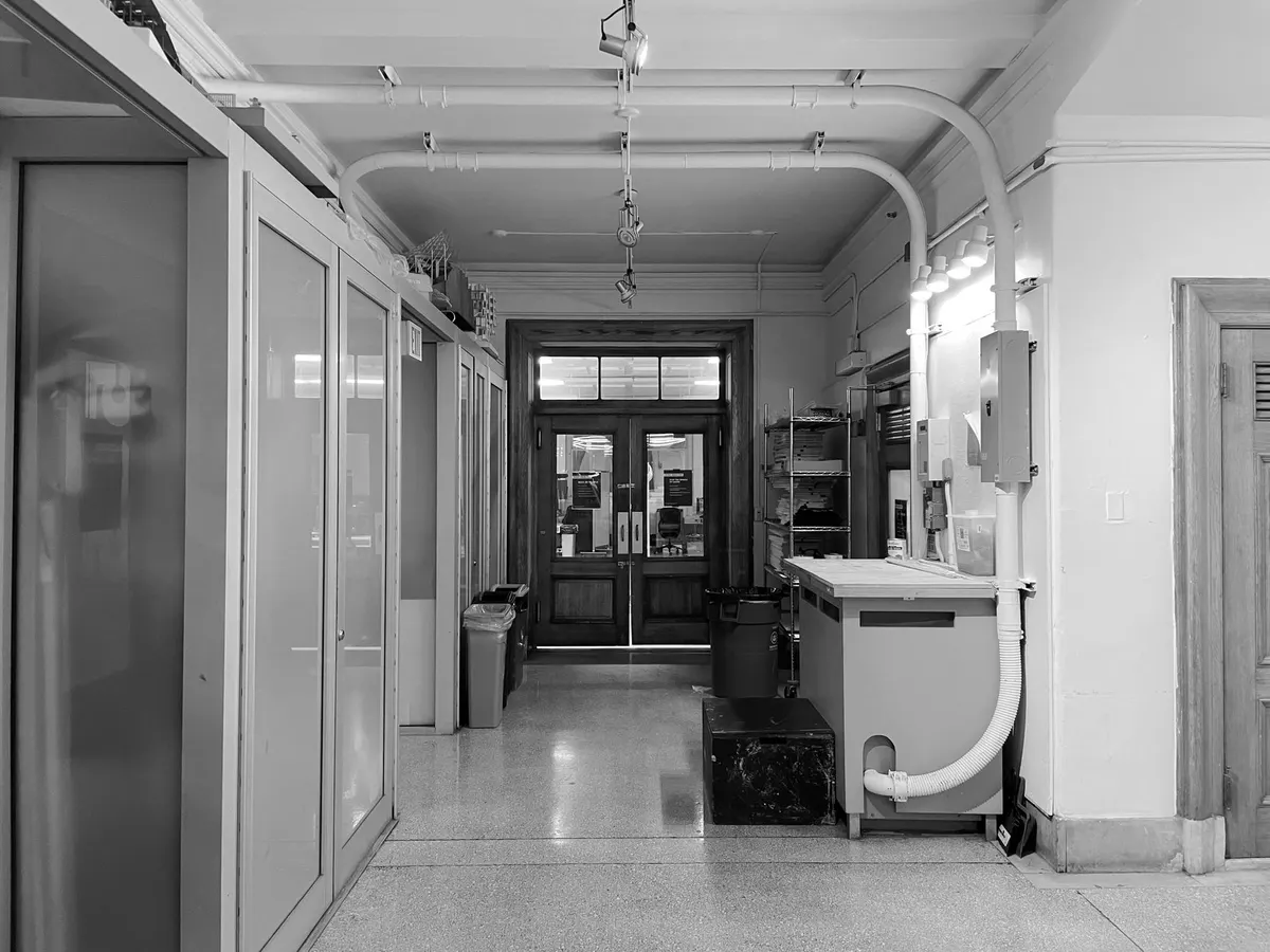 Corridor of a public building with a closed double door at the far end, black-and-white photograph