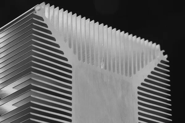 Black and white close-up of the fins of an aluminium heat sink, side-lit against a dark background