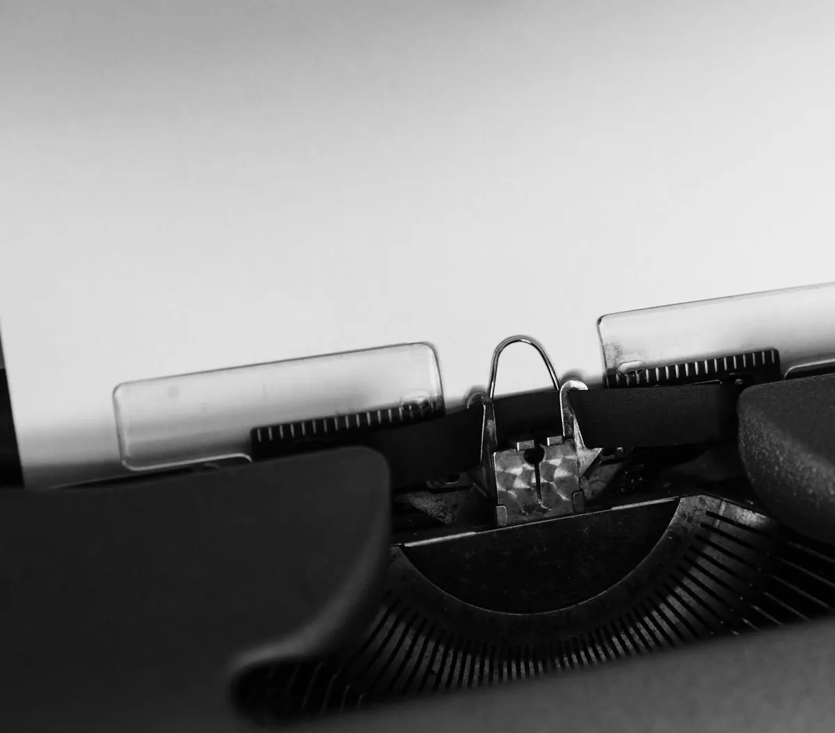 A blank sheet of paper fed into the roller of a typewriter, close-up detail, black-and-white photograph