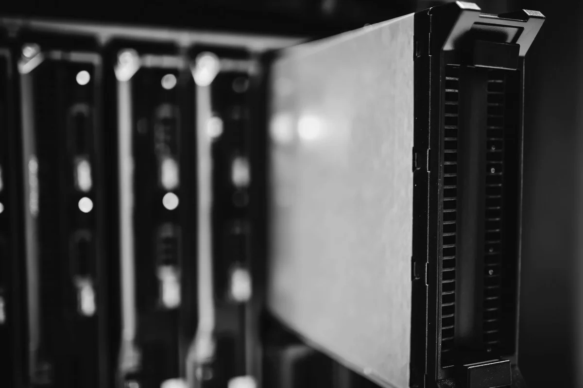 A server module pulled halfway out of a rack in a dark room, black and white photograph