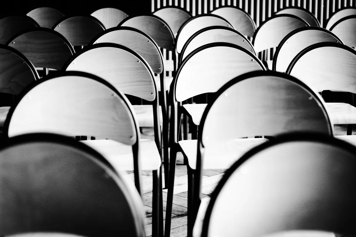 File di sedie vuote in una sala d'attesa, in bianco e nero