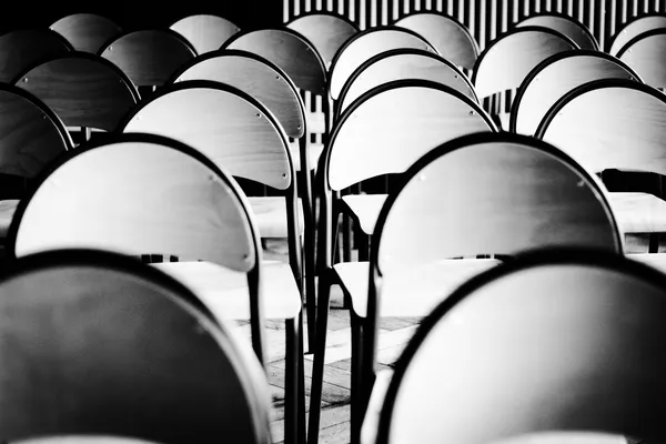 Rows of empty chairs in a waiting room, in black and white
