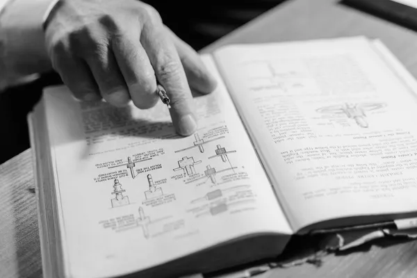 A hand pointing at a technical drawing in an open instruction manual