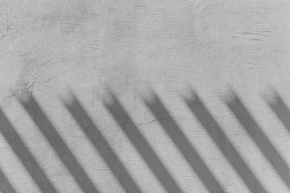 Parallel shadows cast by a structure outside the frame onto a plastered wall, black and white photograph