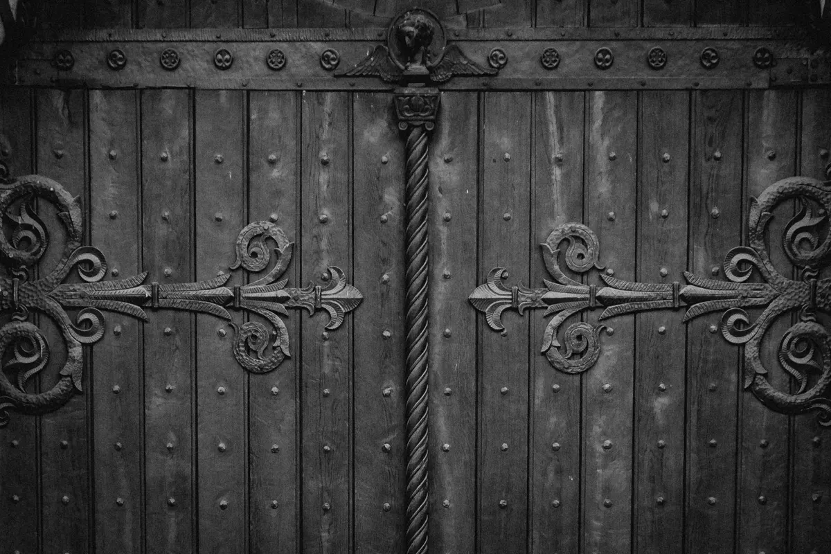 Wrought-iron hinges on a two-leaf wooden door, black and white photograph