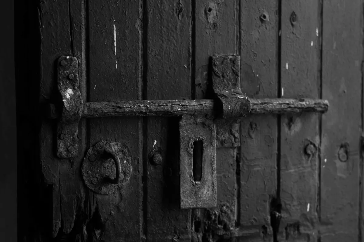 Chiavistello metallico a scorrimento su una porta di legno, fotografia in bianco e nero