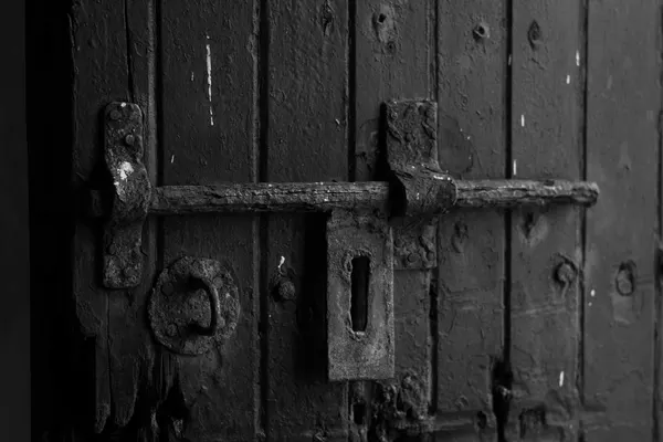 Chiavistello metallico a scorrimento su una porta di legno, fotografia in bianco e nero