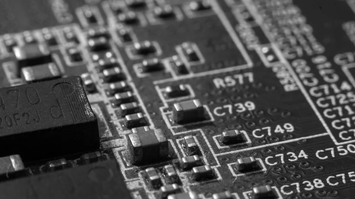 Macro photograph of a printed circuit board with capacitors, resistors and silkscreened reference codes, in black and white