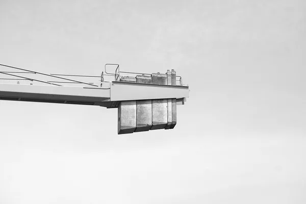 Blocchi di contrappeso in calcestruzzo appesi sotto il braccio di una gru a torre, contro il cielo, fotografia in bianco e nero