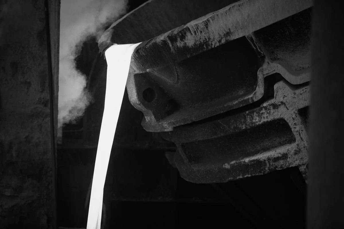 Molten metal being poured in an industrial foundry, in black and white