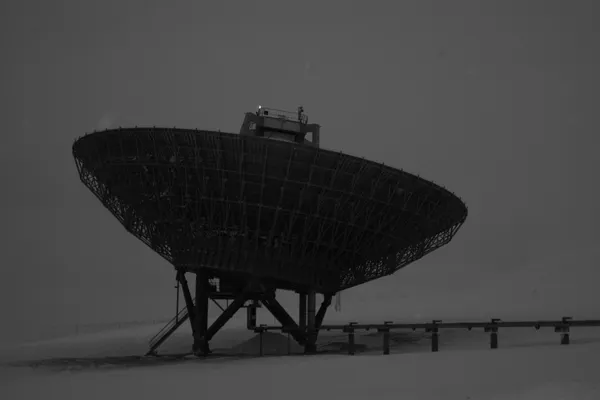 Large radar antenna in an Arctic landscape at dusk
