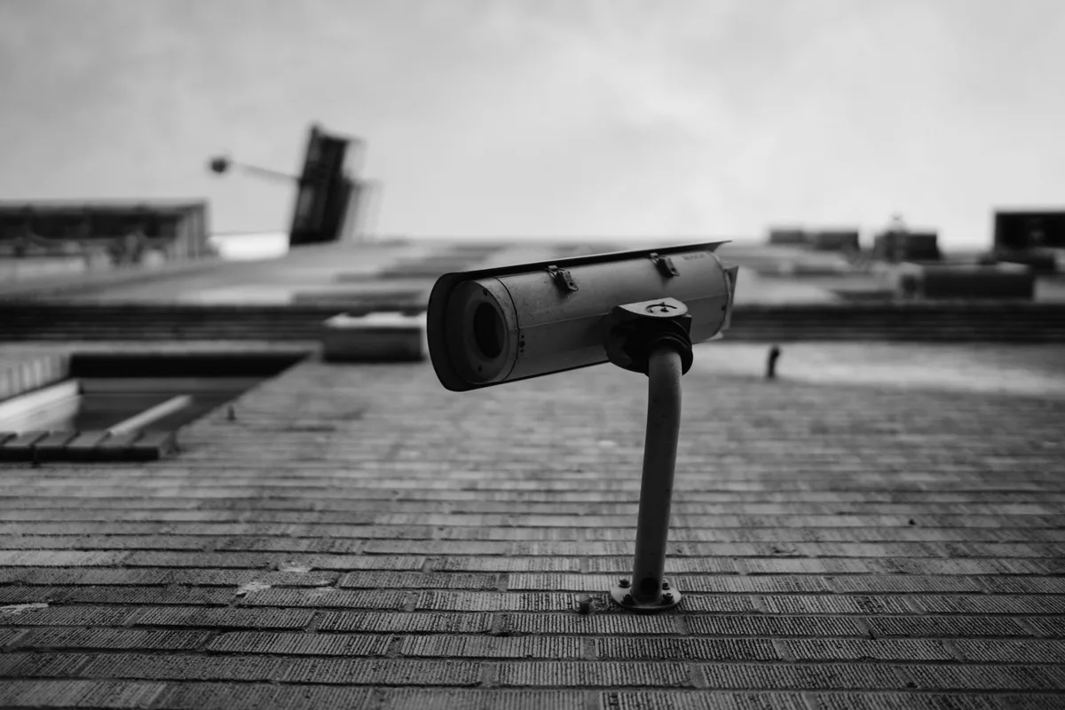 A surveillance camera on a building façade, seen from below