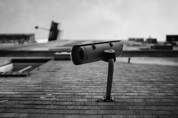 A surveillance camera on a building façade, seen from below