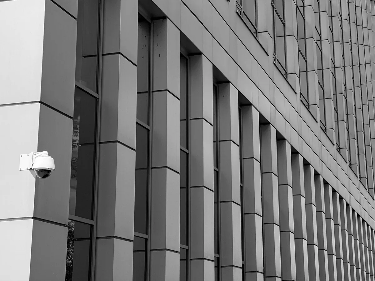 Facade of a modern institutional building with a dome-shaped surveillance camera on the corner