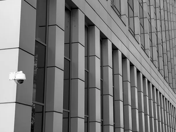 Facade of a modern institutional building with a dome-shaped surveillance camera on the corner