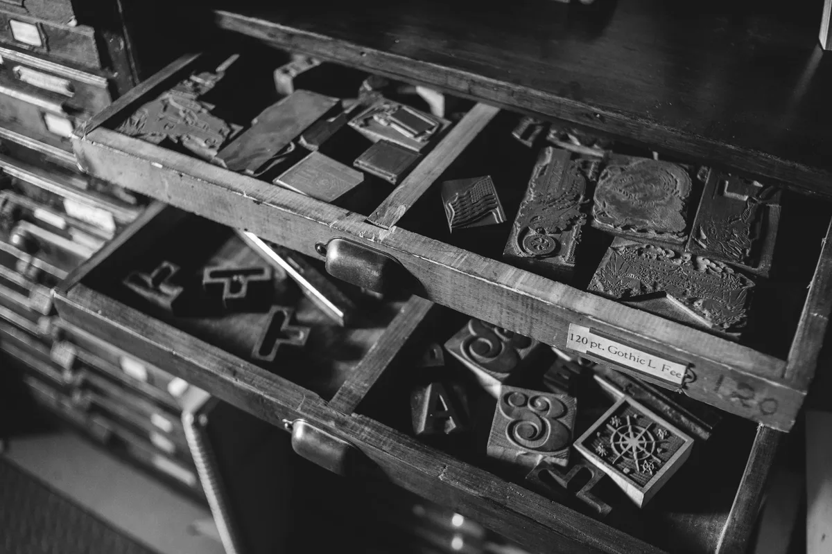 Cassetti aperti di una cassettiera da tipografia con caratteri mobili e matrici in legno e metallo, in bianco e nero