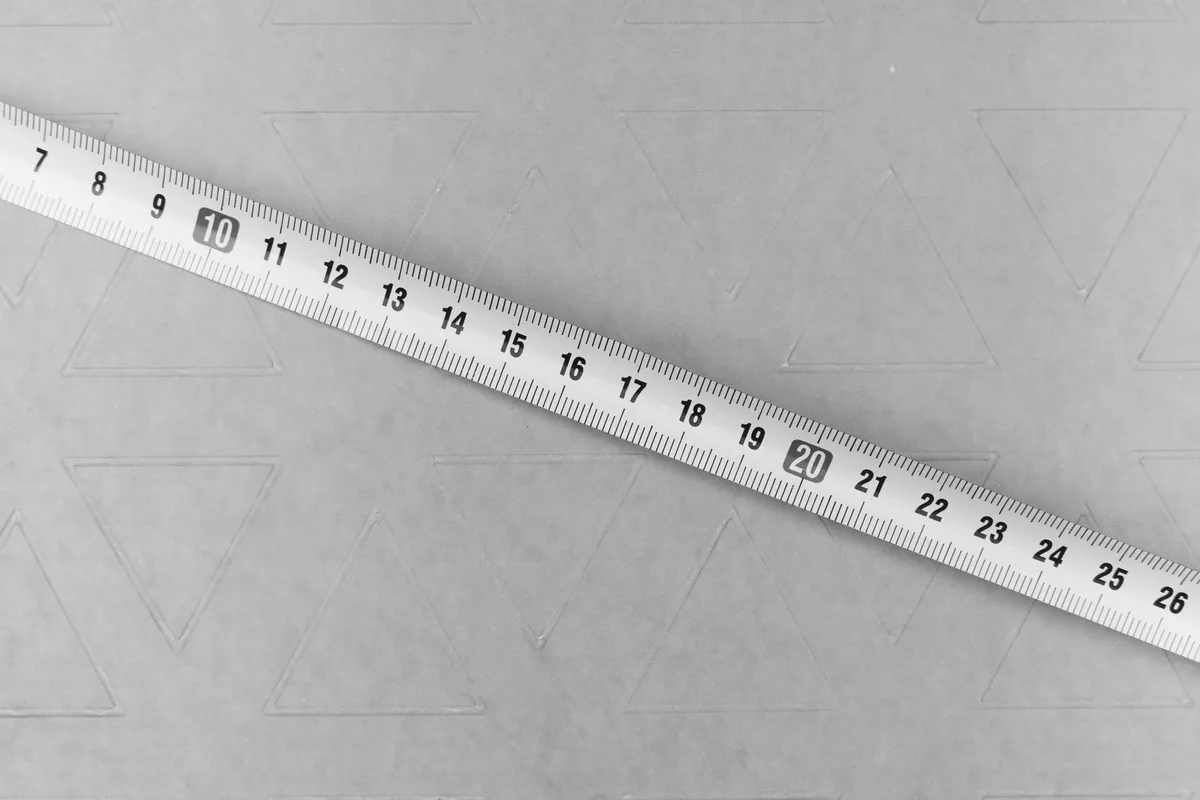 Nastro metrico graduato disteso in diagonale su un cartoncino goffrato, in bianco e nero