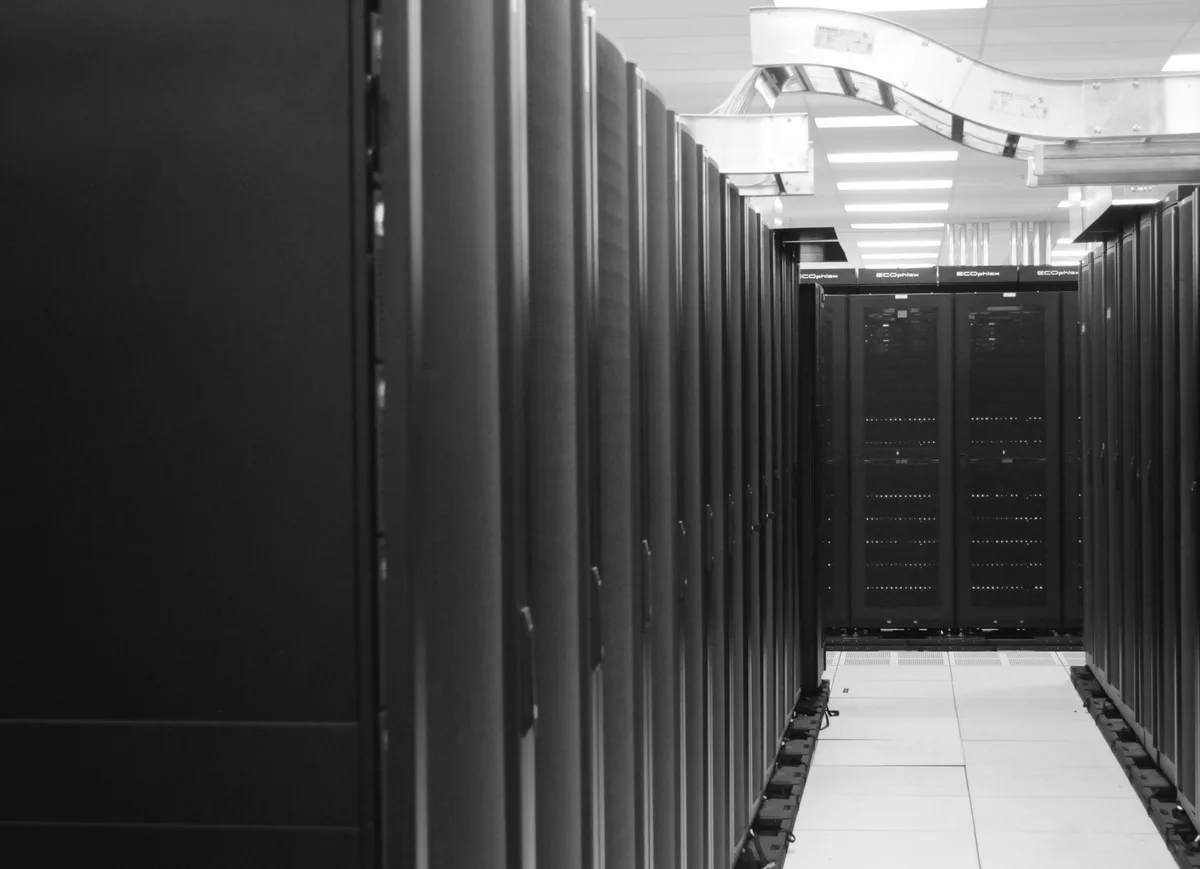 Corridoio di un centro di calcolo con file di armadi server, in bianco e nero