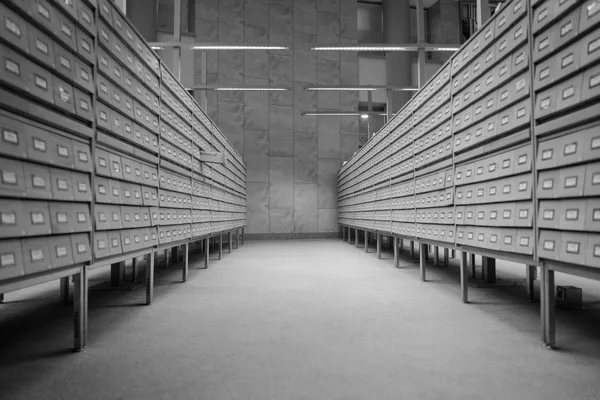 A corridor between two long rows of numbered archive drawers, in black and white