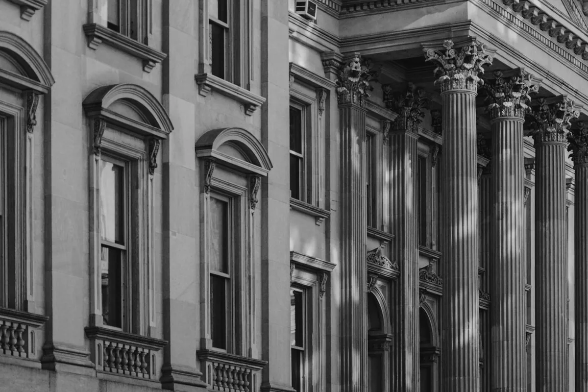 The neoclassical facade of a courthouse with Corinthian columns and pediment, in black and white