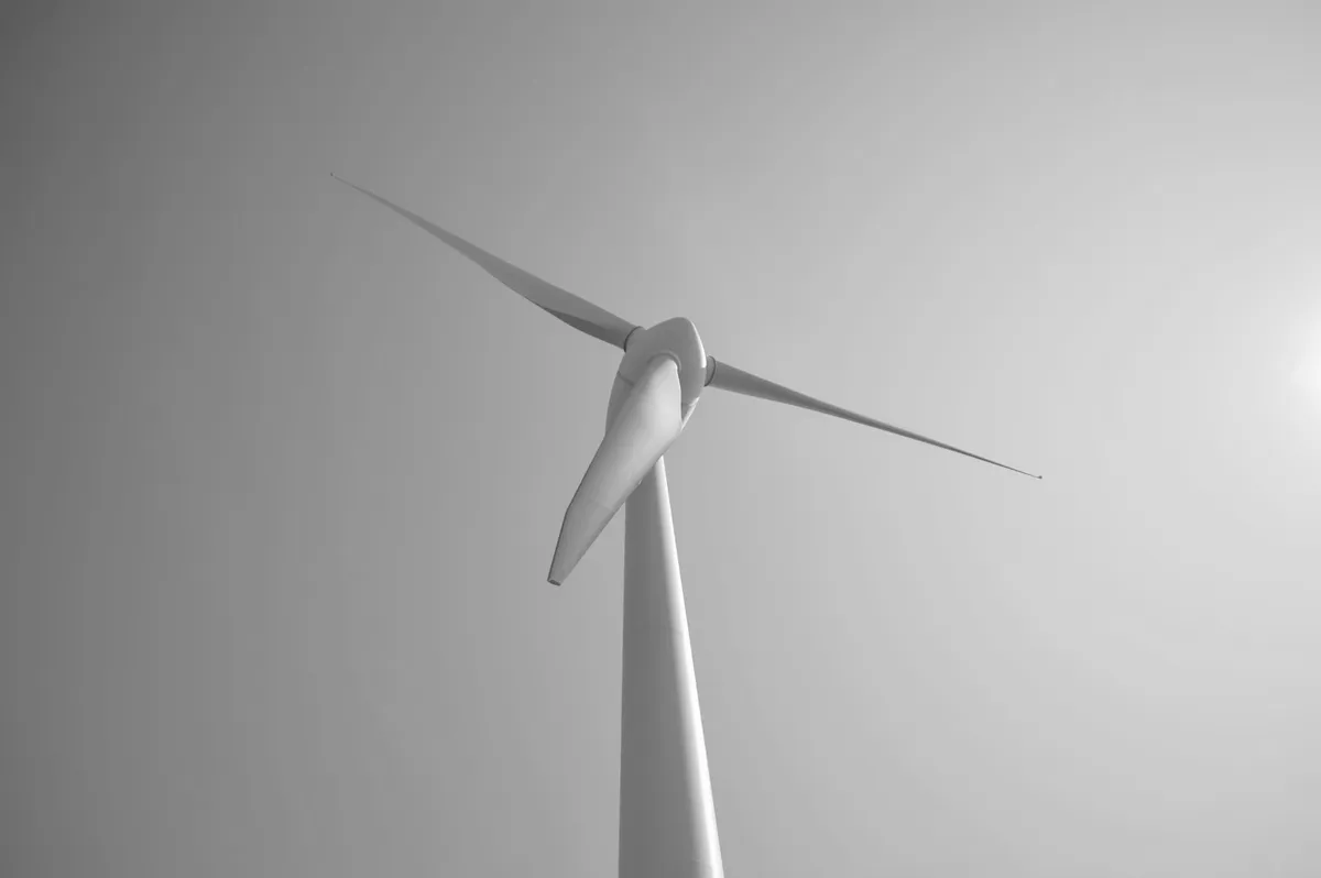 A wind turbine blade seen from below against the sky, black-and-white photograph