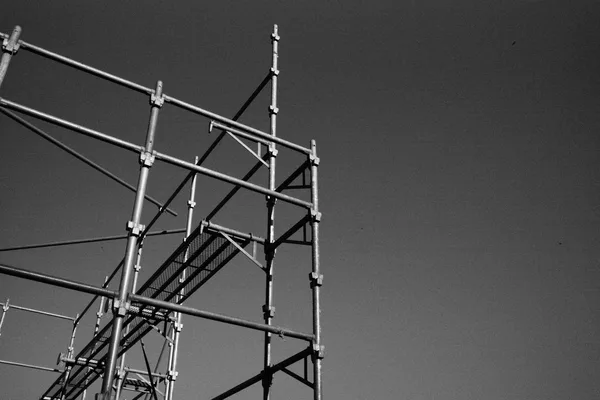 La sommità di un ponteggio tubolare montato contro un cielo vuoto, senza edificio dietro, fotografia in bianco e nero, nessuna persona