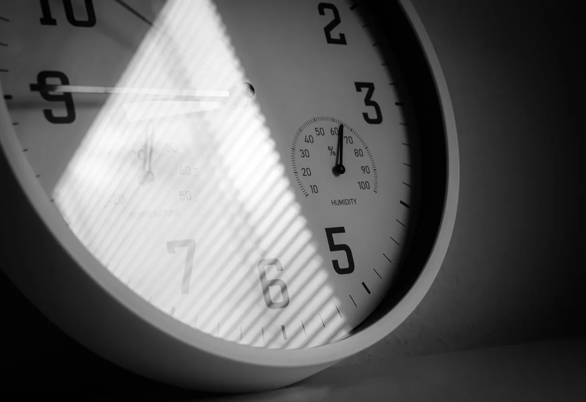 Primo piano del quadrante di un orologio da parete con un secondo strumento a lancetta al suo interno, in bianco e nero