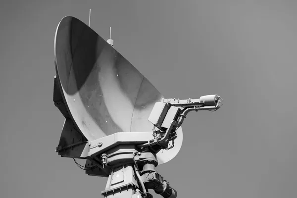 Antenna parabolica di un radar di puntamento, ripresa dal basso contro un cielo senza nuvole, fotografia in bianco e nero