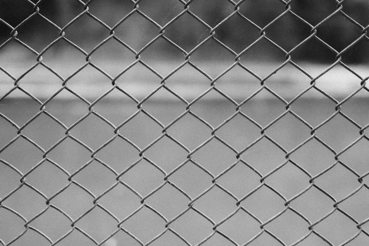 Diamond-pattern metal fencing photographed close up, in black and white, with no people and no legible text