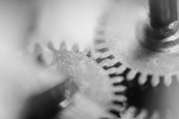 Denti di due ingranaggi metallici impolverati che si incastrano, fotografia macro in bianco e nero