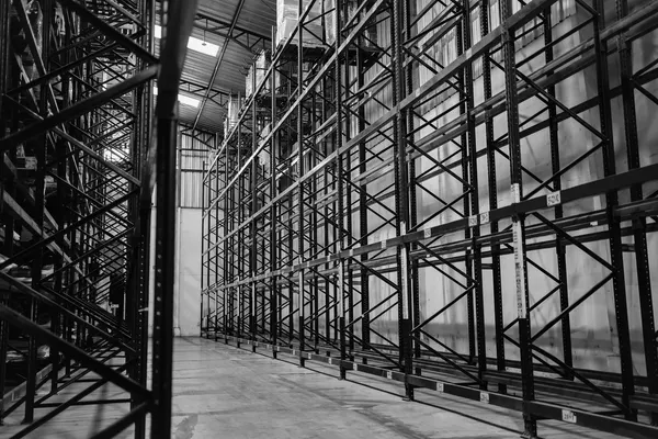 Corridoio di una scaffalatura industriale in acciaio, alta e completamente vuota, in un capannone logistico, fotografia in bianco e nero