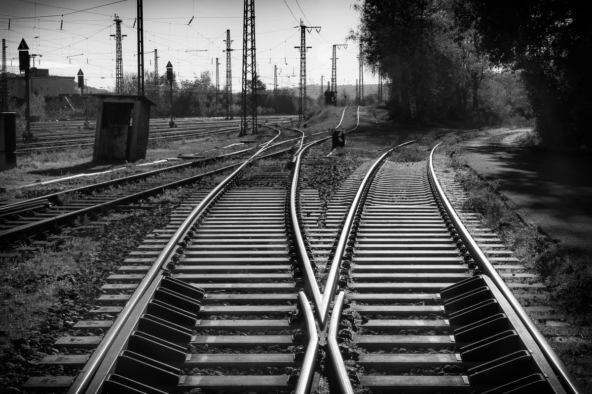 Scambi ferroviari in bianco e nero: due binari si incrociano e proseguono in un fascio di linee parallele