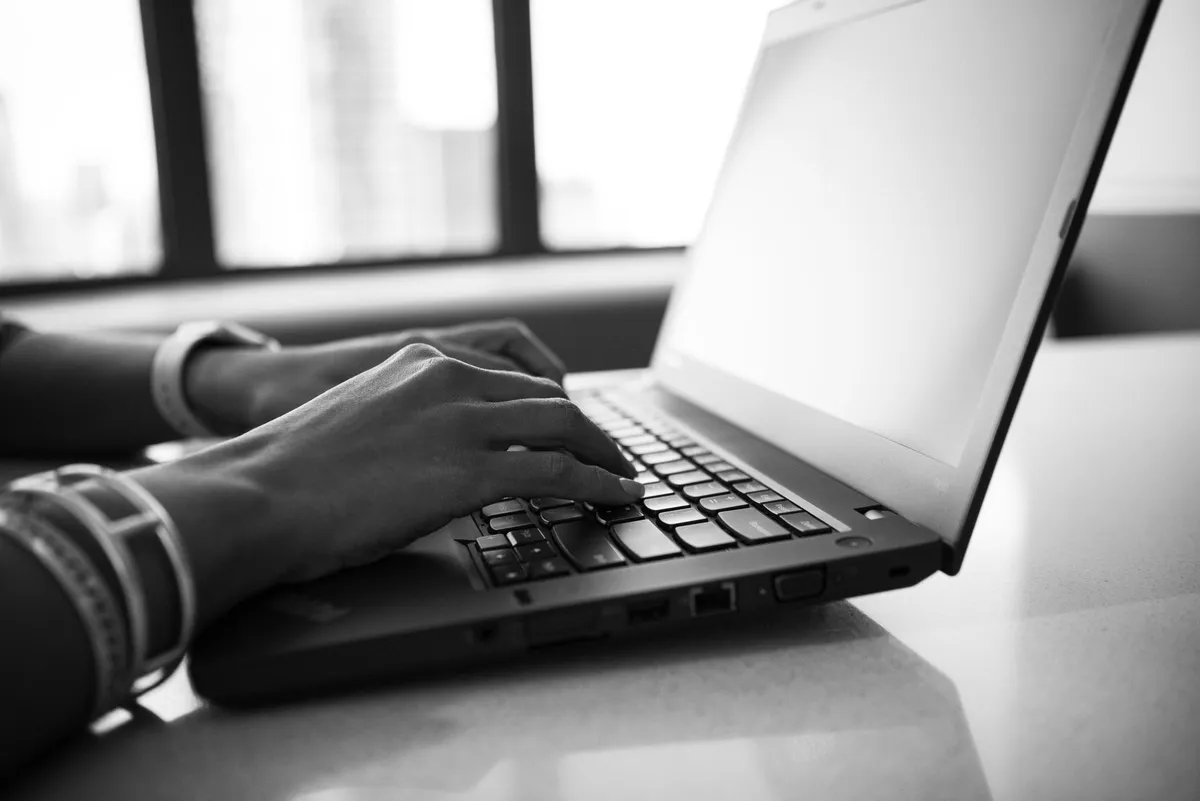 Mani che digitano su una tastiera di un computer portatile in un ufficio