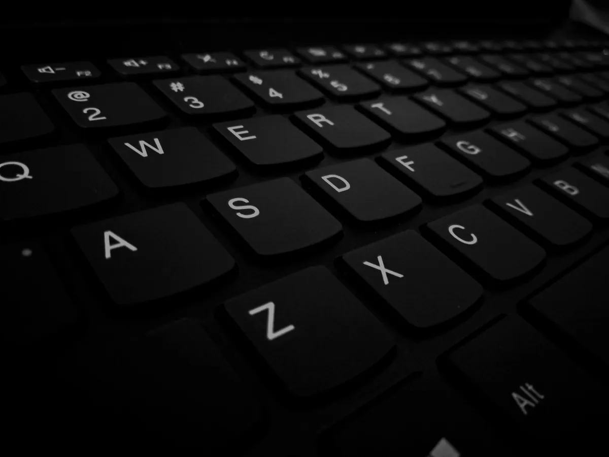 Black-and-white close-up of computer keyboard keys, shot at an angle against backlight