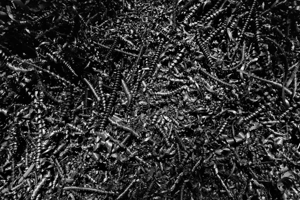 Primo piano in bianco e nero di trucioli metallici a spirale ammassati, texture caotica e riflettente