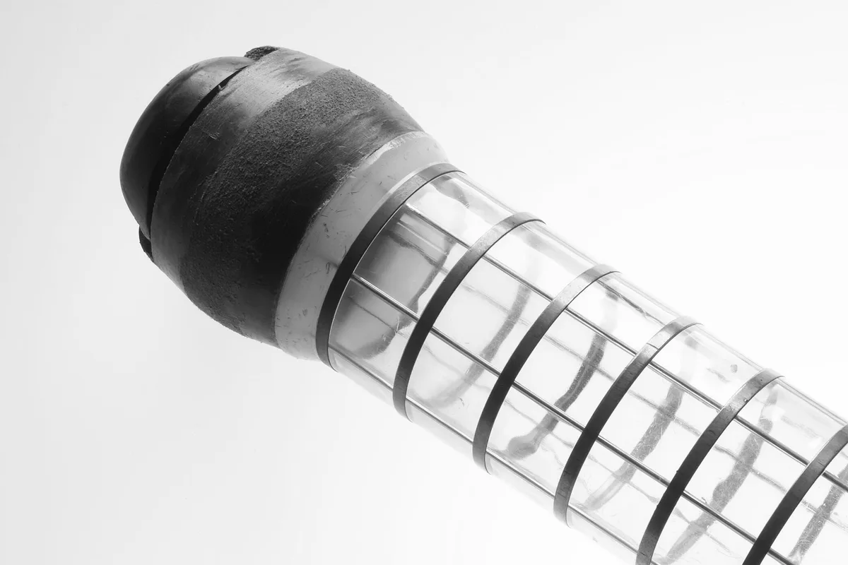 Il bossolo di un impianto di posta pneumatica, tappo in gomma e anelli metallici sul corpo trasparente, fotografia in bianco e nero