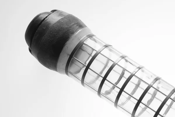 Il bossolo di un impianto di posta pneumatica, tappo in gomma e anelli metallici sul corpo trasparente, fotografia in bianco e nero