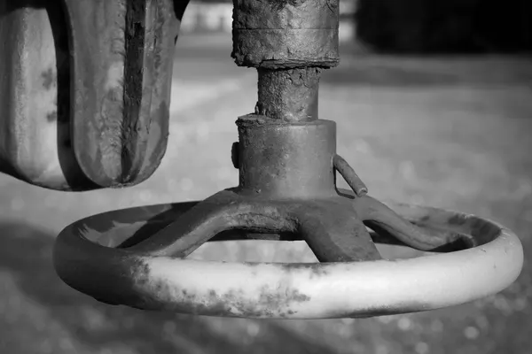 Volantino di una valvola industriale arrugginita, ripreso da vicino, fotografia in bianco e nero
