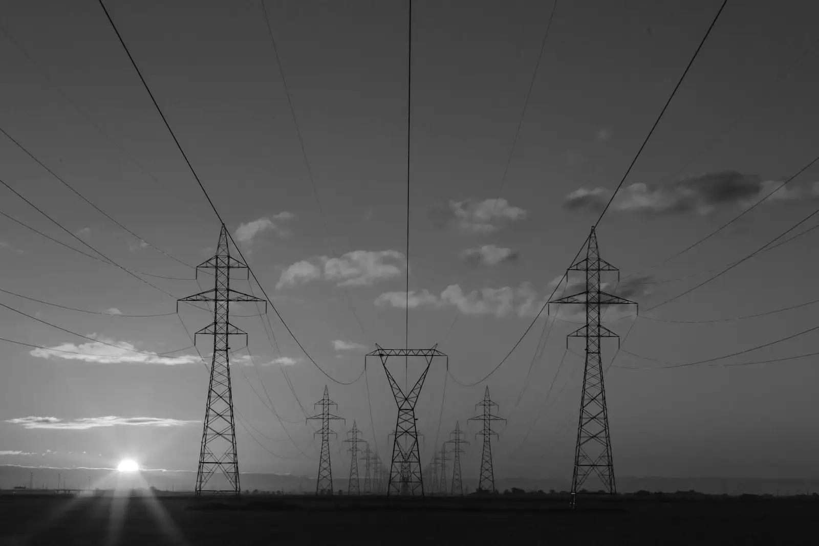 High-voltage transmission towers of a power grid at sunset